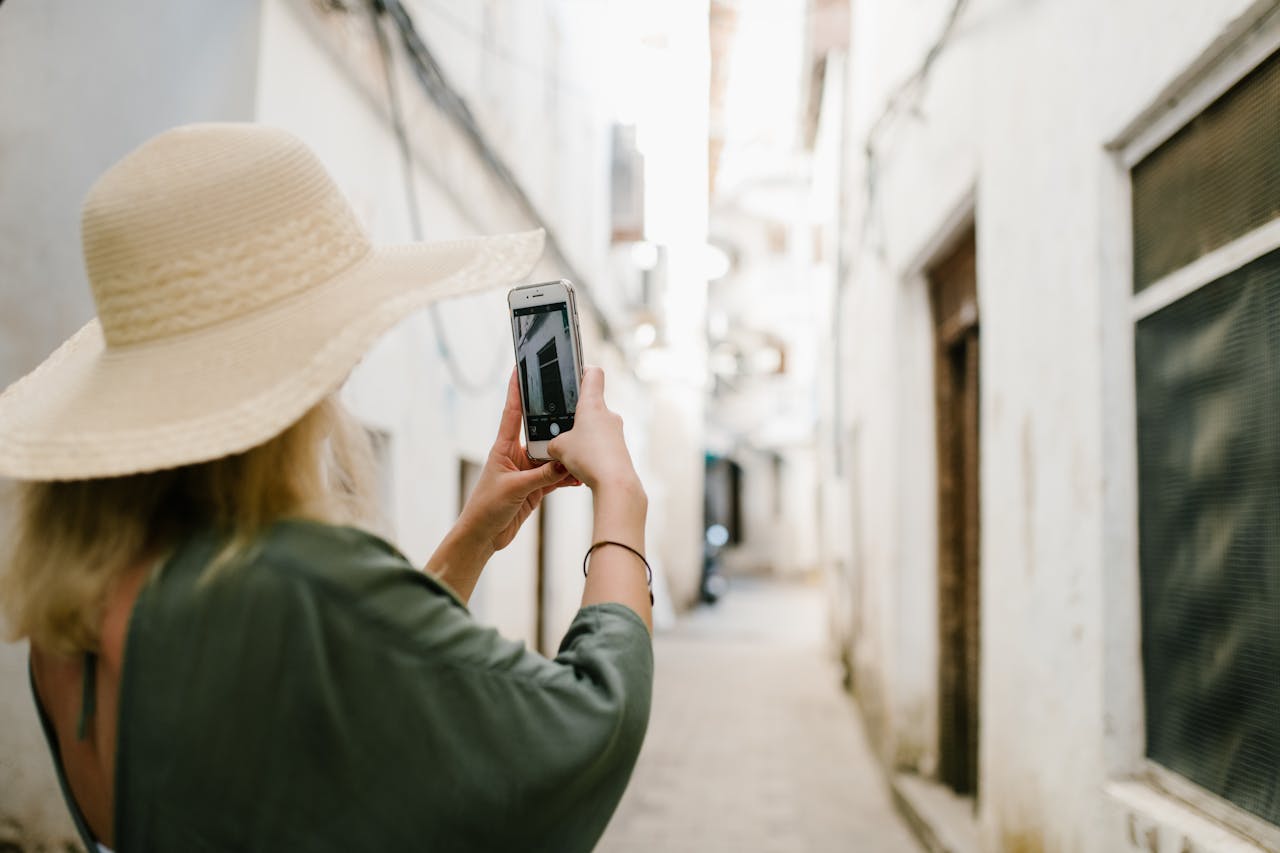 A woman capturing a photo in a historic narrow alleyway with her smartphone.